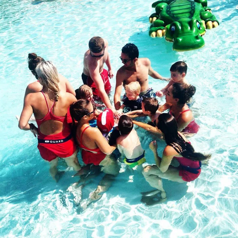 Lifeguards and kids doing a group huddle in the pool